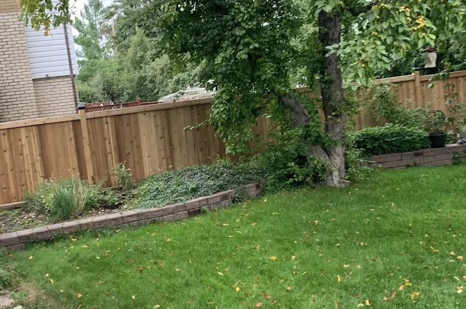 Side view of the cedar fence running beside a retaining wall and planting beds