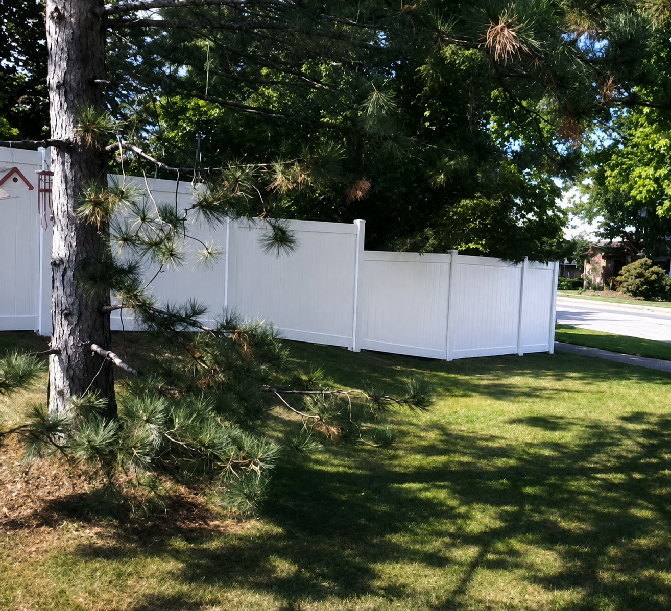 White PVC privacy fence with stepped panels running along a shaded Ottawa front yard