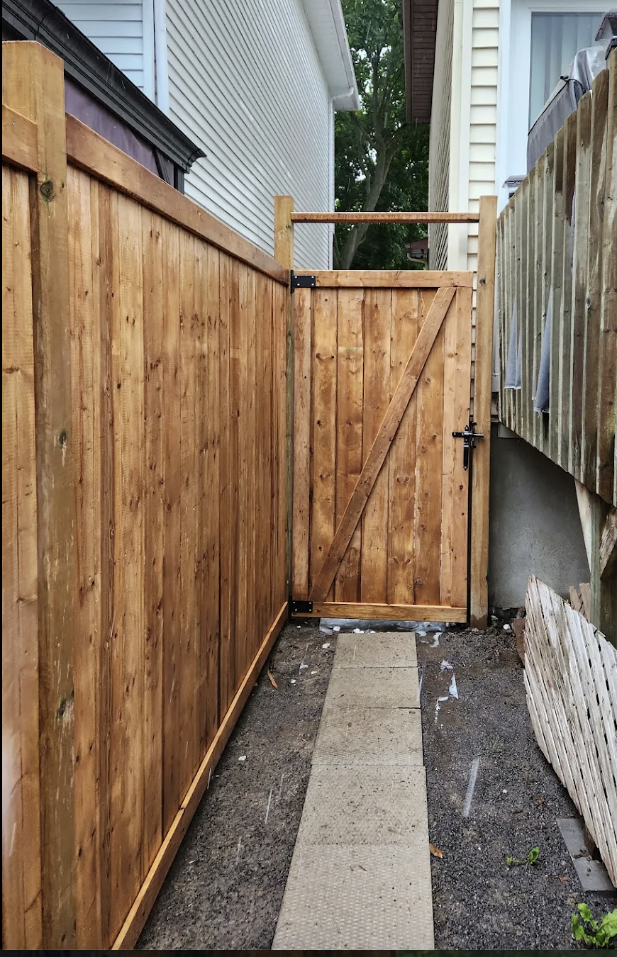 Matching cedar gate with diagonal bracing and black hardware in a narrow side passage