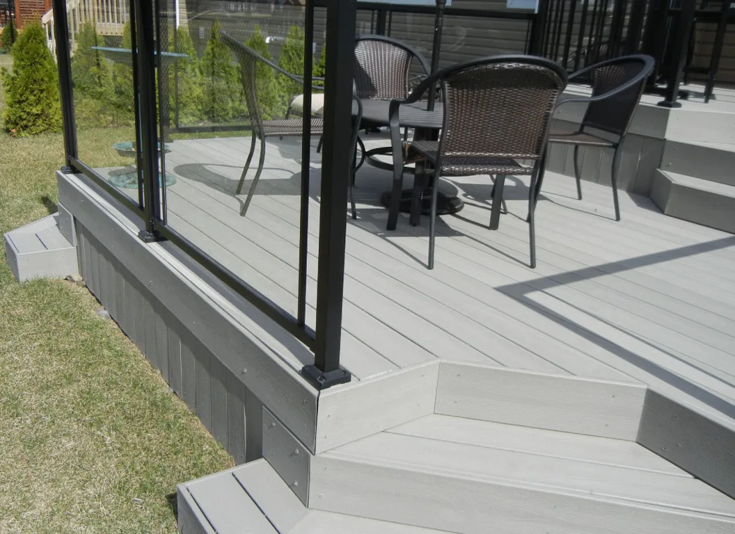 Grey composite backyard deck with black aluminum railings and steps.