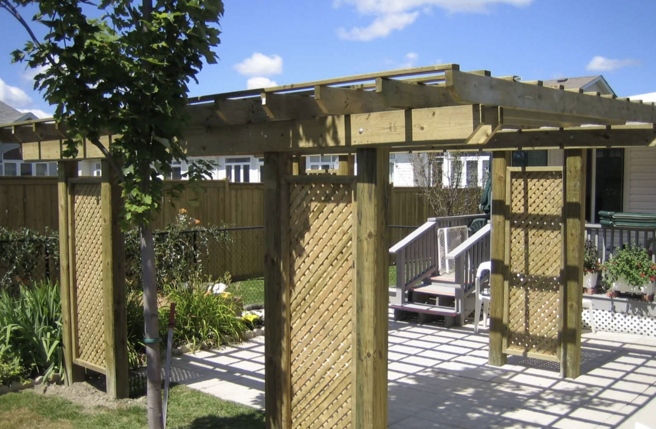 Pergola with Lattice Privacy Panels installed in Kanata, Ontario by Fence Masters Ottawa — Heavy-timber pergola over an interlock patio with diagonal lattice privacy walls