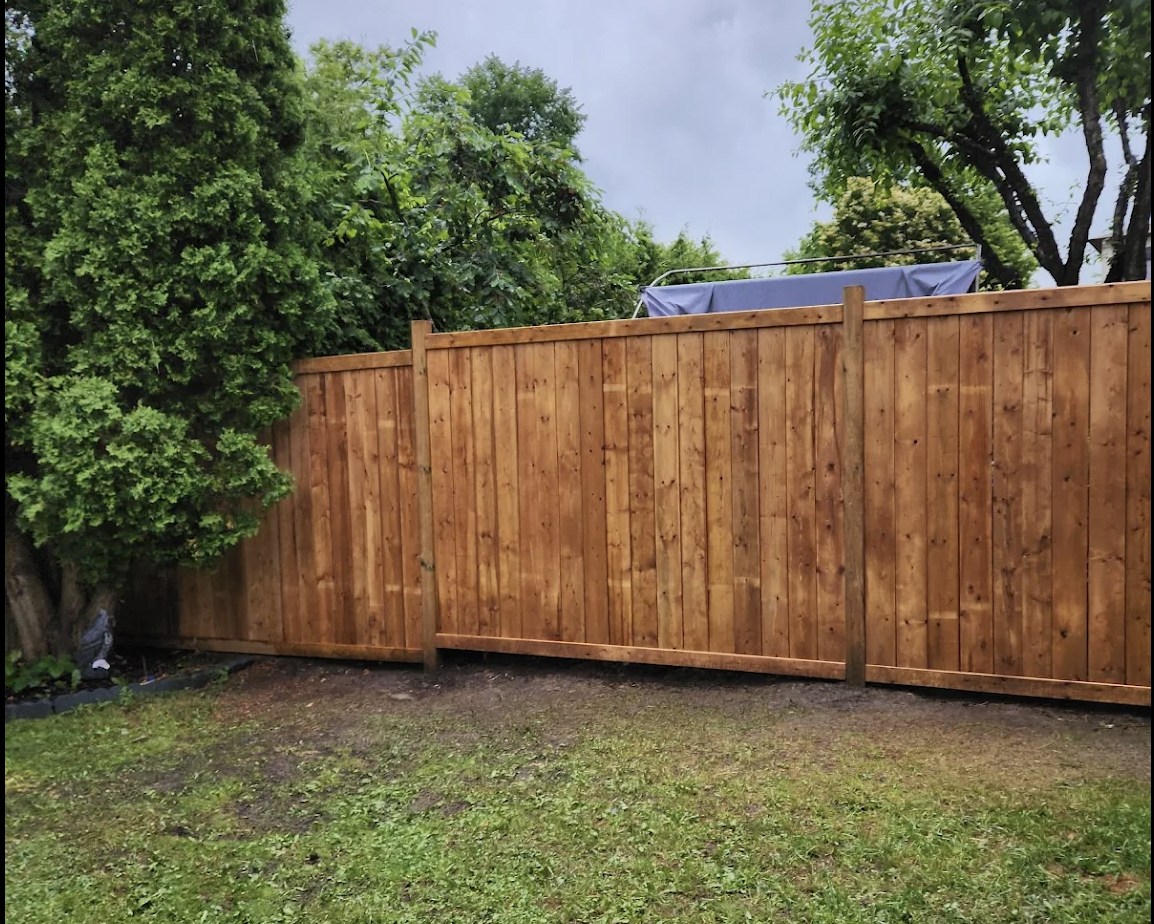 Wood privacy fence spanning the rear property line of a landscaped Ottawa backyard