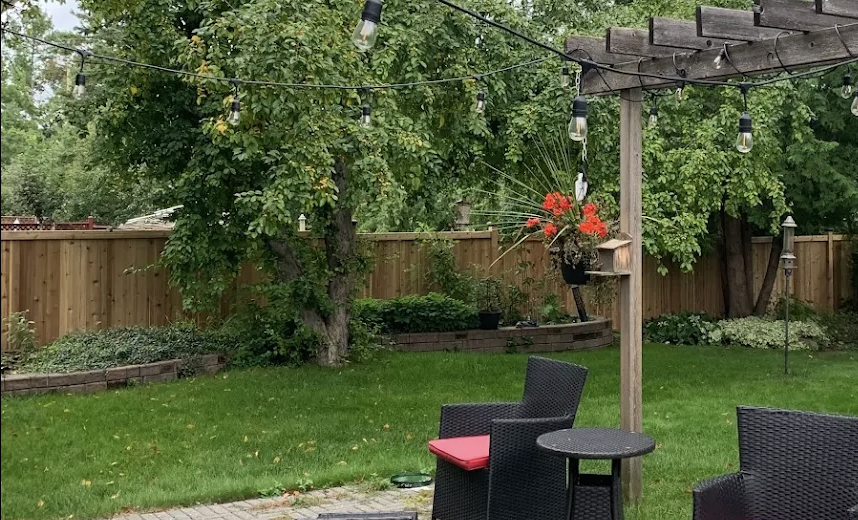 Backyard patio with string lights and pergola framed by the new wood fence